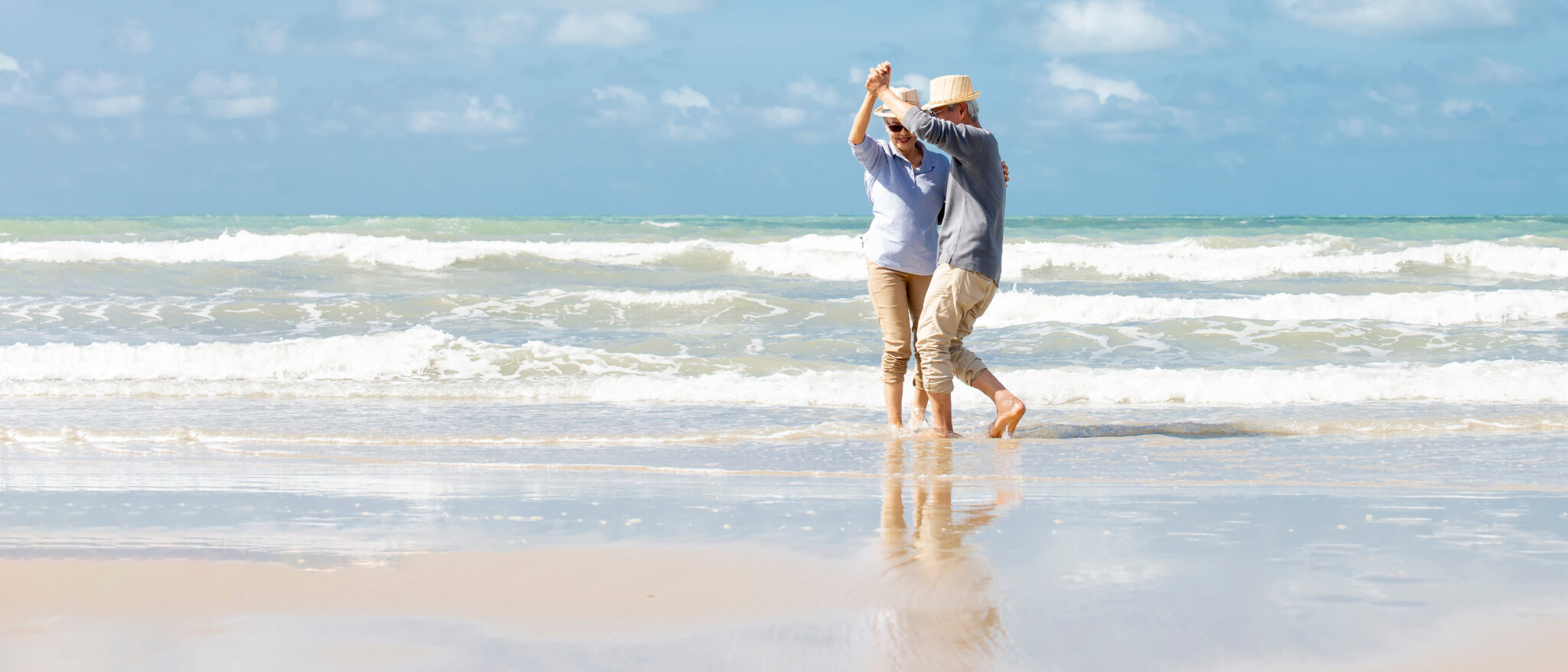 Elderly couple dancing on a beach.