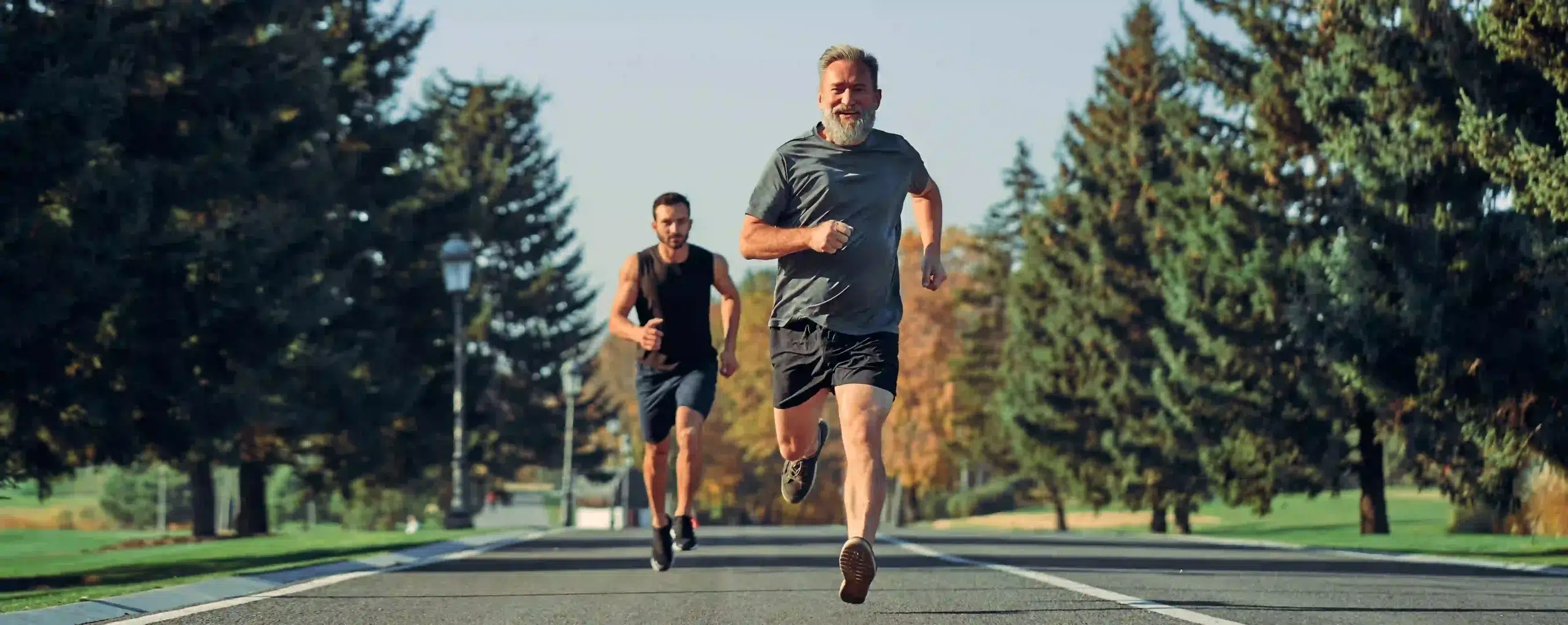 Two men of different ages running together on a path, representing active aging and mobility.