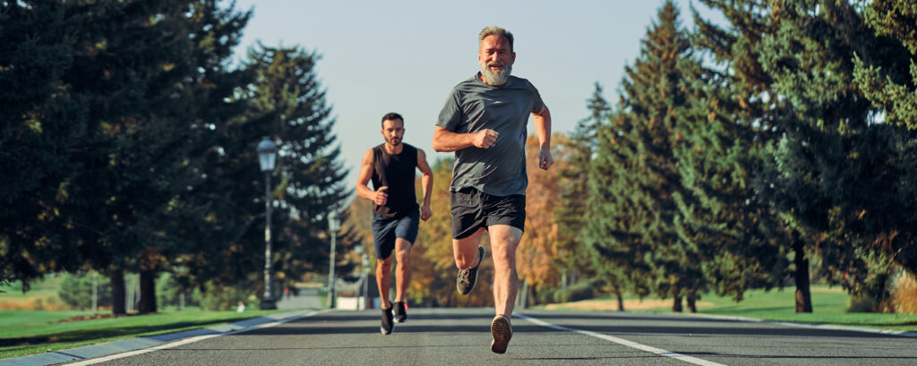 Two men of different ages running together on a path, representing active aging and mobility.